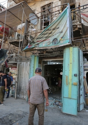 عراقيون يتفقدون موقع انفجار عبوة قرب ساحة التحرير وسط بغداد