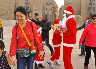 "بابا نويل" في معبد الأقصر.. شباب يوزعون هدايا على الأجانب: مصر آمان