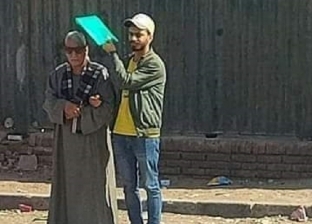 شاب يحمي والده من أشعة الشمس أمام مستشفى بأسيوط.. «رفع إيده ربع ساعة»