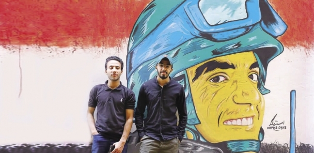 «أحمد» وصديقه «محمود» بجوار اللوحة