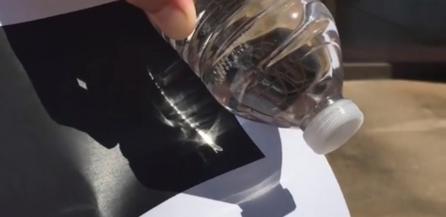 استخدام زجاجة مياه الكثيف أشعة الشمس واشعال ورقة