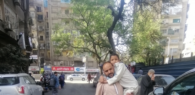 شايل ابنه علي كتفه بقاله أربع سنين في رحلة يومية من أطفيح ل القاهرة للعلاج