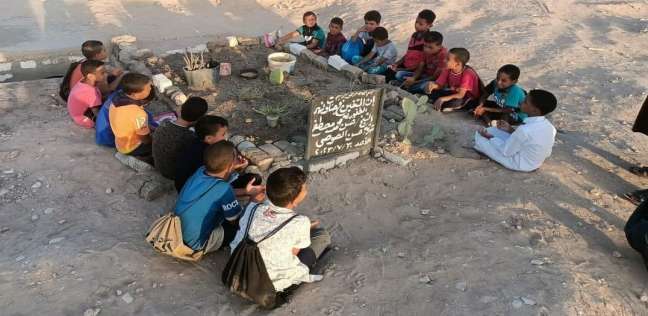 الأطفال يقرأون القرآن على قبر معلمهم