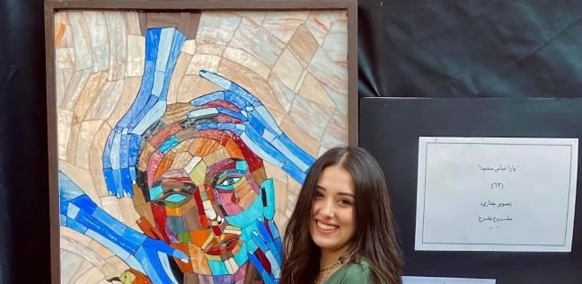يارا عباس بجوار مشروع تخرجها وهي لوحة «الإنهيدونيا»