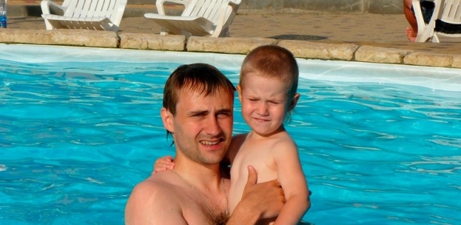 الأب المتهم "أوليج دراشيف" يحمل ابنه "إيليا" في حمام السباحة