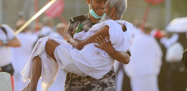 رجل أمن سعودي يحمل حاجا مسنا