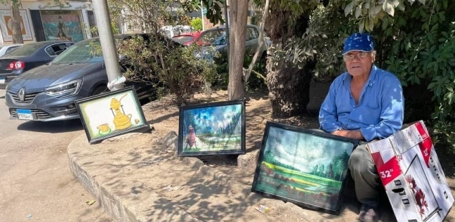 ياسر عبدالحميد إلى جوار لوحاته على الرصيف