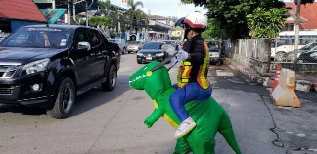 سائقون في تايلاند يتفاجأون بـ"ديناصور" ينظّم حركة المرور
