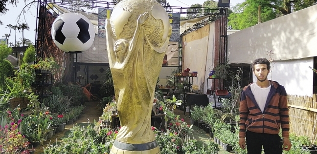 أحد عمال المعرض بجانب مجسم كأس العالم