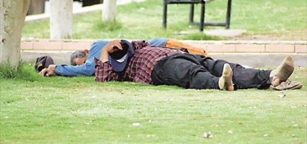 مواطنان يهربان من حر الصيف بالنوم فى الحدائق العامة