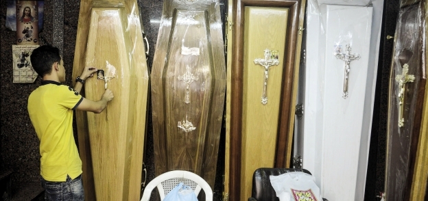أحد عمال المحل أمام صناديق تشييع الموتى من المسيحيين
