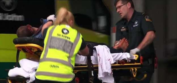 أفراد من الشرطة النيوزيلندية أثناء نقل أحد المصابين من مكان الحادث «أ.ف.ب»