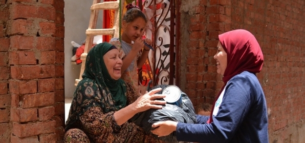 مندوبة جمعية خيرية أثناء تسليم مساعدات لسيدة فقيرة