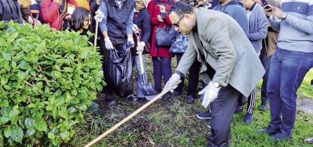 محافظ الإسكندرية أثناء مشاركته الشباب تنظيف أرض حديقة الشلالات