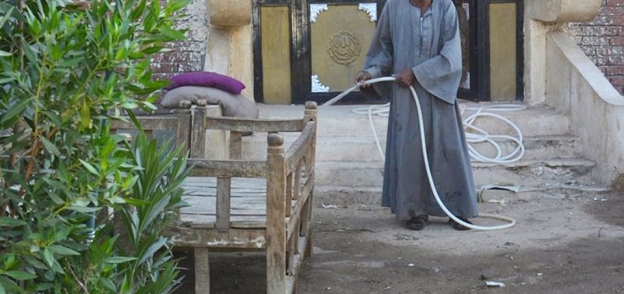 مواطن يرش المياه أمام منزله فى قنا