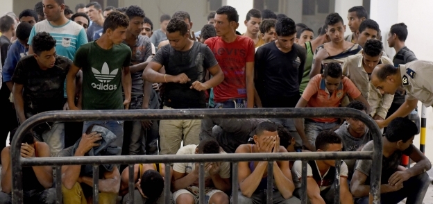 الشباب المصريون الناجون من الغرق أثناء التحفظ عليهم بعد الحادث «أ.ف.ب»