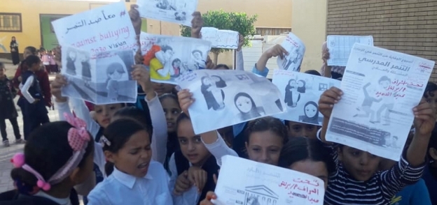 الطلاب داخل المدرسة وهم يرفعون لافتات ضد التنمر