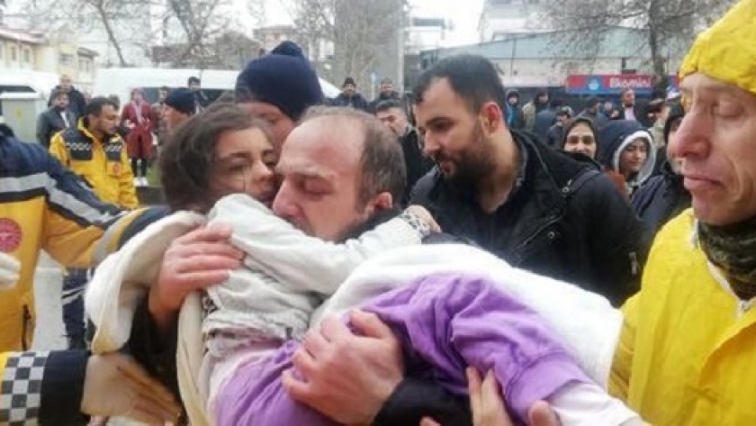 أب يحمل طفلته بعد عملية الإنقاذ