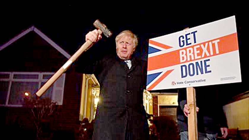 رئيس وزراء بريطانيا يمسك لافته عن بريكست وفي اليد الأخرى مطرقة
