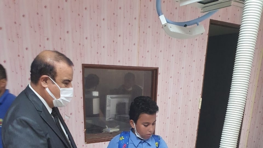 الطالب أحمد مع وكيل وزارة التربية والتعليم بمطروح خلال إجراء الأشعة علية يدية بعد اعتداء معلم عليه