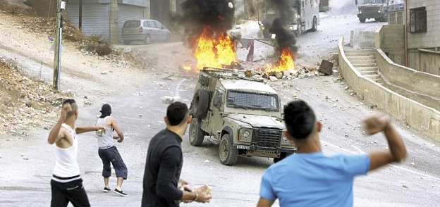 شباب فلسطينيون يواجهون مدرعات الاحتلال بالحجارة «أ.ف.ب»