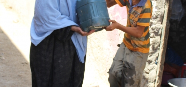 سيدة وابنها يقومان بتخزين المياه