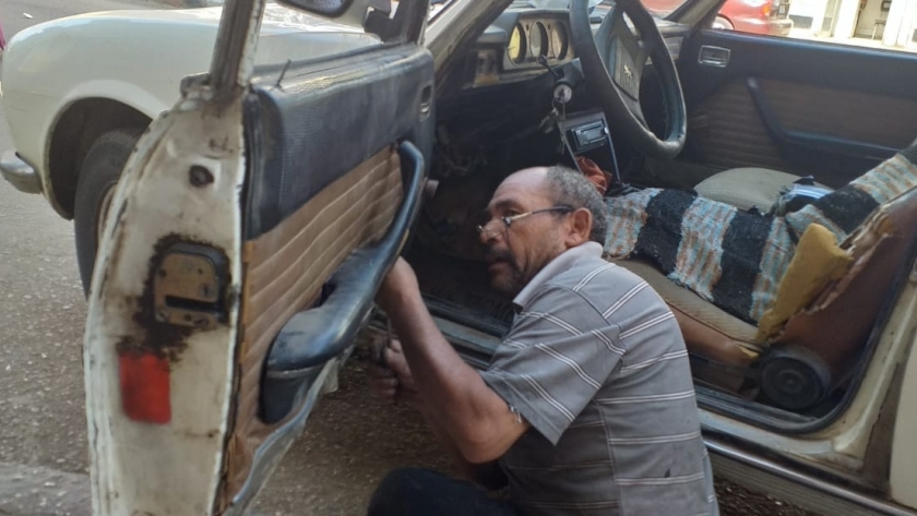 "محمد" يمارس عمله فى سيارة قديمة بورشته