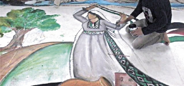 «مؤمن» يرسم سيدة ترقص بالزى الفلسطينى المميز