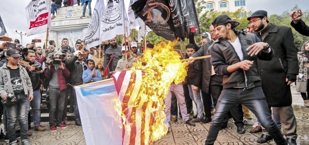 محتجون فلسطينيون يحرقون الأعلام الأمريكية والإسرائيلية في مدينة غزة أمس «أ.ف.ب»