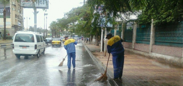 عمال النظافة في الإسكندرية يشاركون في ازاحة مياه الأمطار من الشوارع