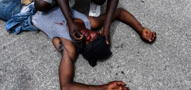 متظاهر ينزف من جرح على رأسه ملقى على الرصيف في هايتي