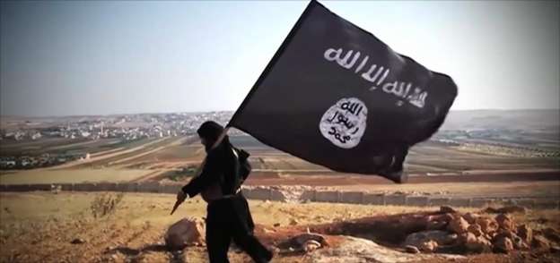 أحد عناصر داعش يرفع علم التنظيم- صورة أرشيفية