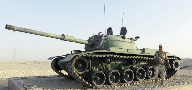 جندى مصرى يقف مبتسماً أمام إحدى الدبابات فى «جبل المر»