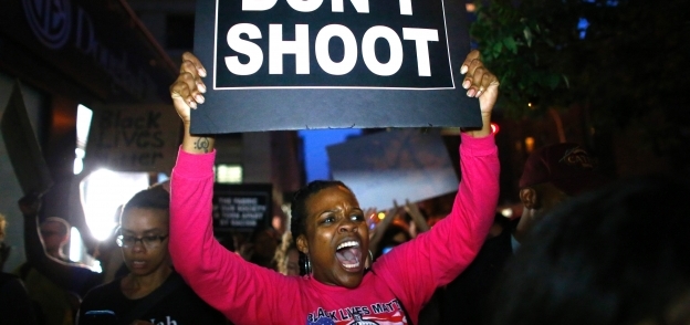 مواطنة أمريكية من السود تحمل لافتة «لا للقنص» فى مظاهرة ضد الشرطة «أ. ف. ب»