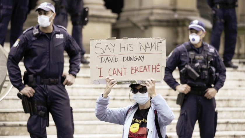 امرأة تحمل لافتة أثناء تجمع لمتظاهرين فى أستراليا لدعم السود