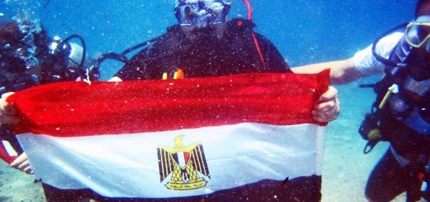 بالصور| رئيس مدينة دهب يرفع علم مصر تحت الماء احتفالا بالقناة