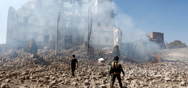 عناصر الحوثيين يعاينون موقعاً يسيطرون عليه بعد تدميره فى غارات التحالف العربى