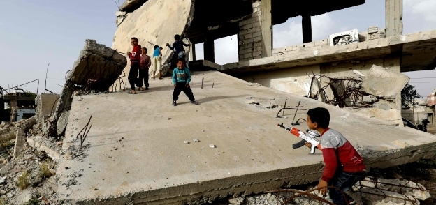 أطفال سوريون يلعبون فوق ركام أحد المنازل فى كوبانى