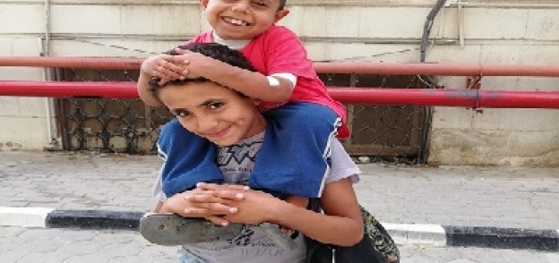 «أحمد» يحمل شقيقه المريض
