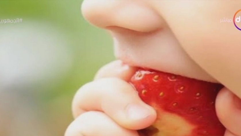 طفل يتناول حبة فراولة
