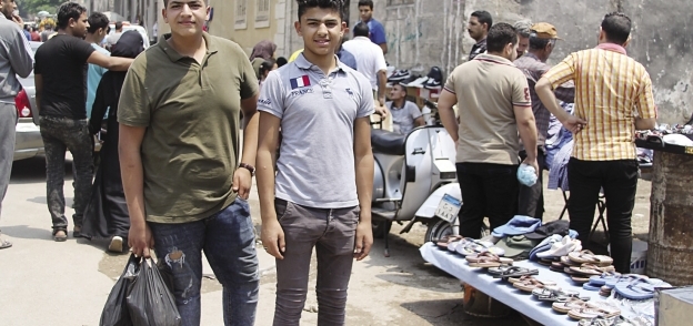 يوسف سيد مع أحد أصدقائه بعد شراء ملابس العيد من رصيف السيدة عائشة