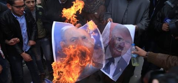 محتجون فلسطينيون يحرقون صور الرئيس الأمريكي دونالد ترامب، ورئيس الوزراء الإسرائيلي بنيامين نتنياهو،