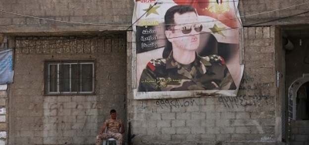 جندى يجلس وبجواره صورة الرئيس السورى بشار الأسد فى إحدى ضواحى مدينة دوما
