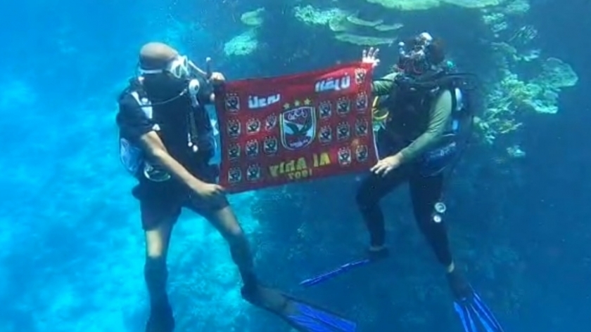بيجو وابنه يحملان علم الأهلي تحت الماء
