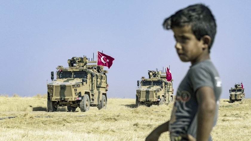 طفل سورى يشاهد دورية تركية أثناء دخولها الأراضى السورية «أ.ف.ب»