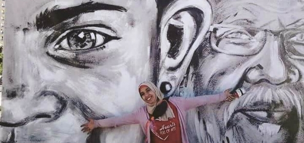 «مها» أمام إحدى الجداريات التى رسمتها فى شوارع أسوان