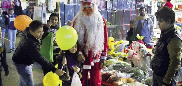 البائع مرتدياً ملابس بابا نويل وحوله الأطفال