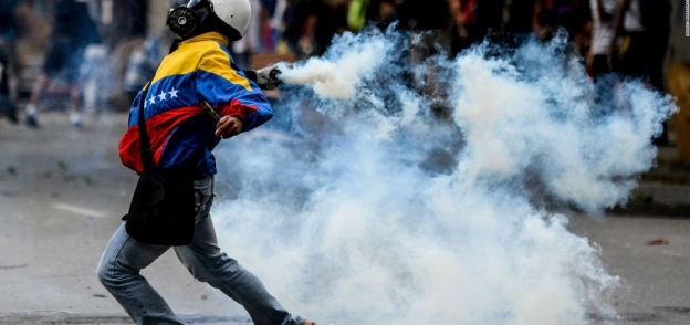 متظاهر يحمل قنبلة مسيلة للدموع في فنزويلا