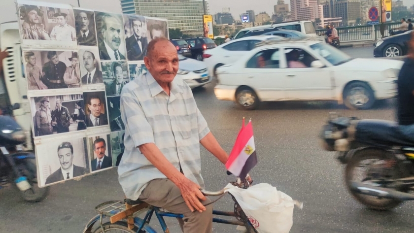 عم حنفي يجوب الشوارع بدراجته وفوقها لوحة تحمل صور نجوم زمن الفن الجميل