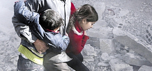 مواطن سورى يفر بأبنائه من الغارات على بلدة جسرين بالغوطة «أ.ف.ب»